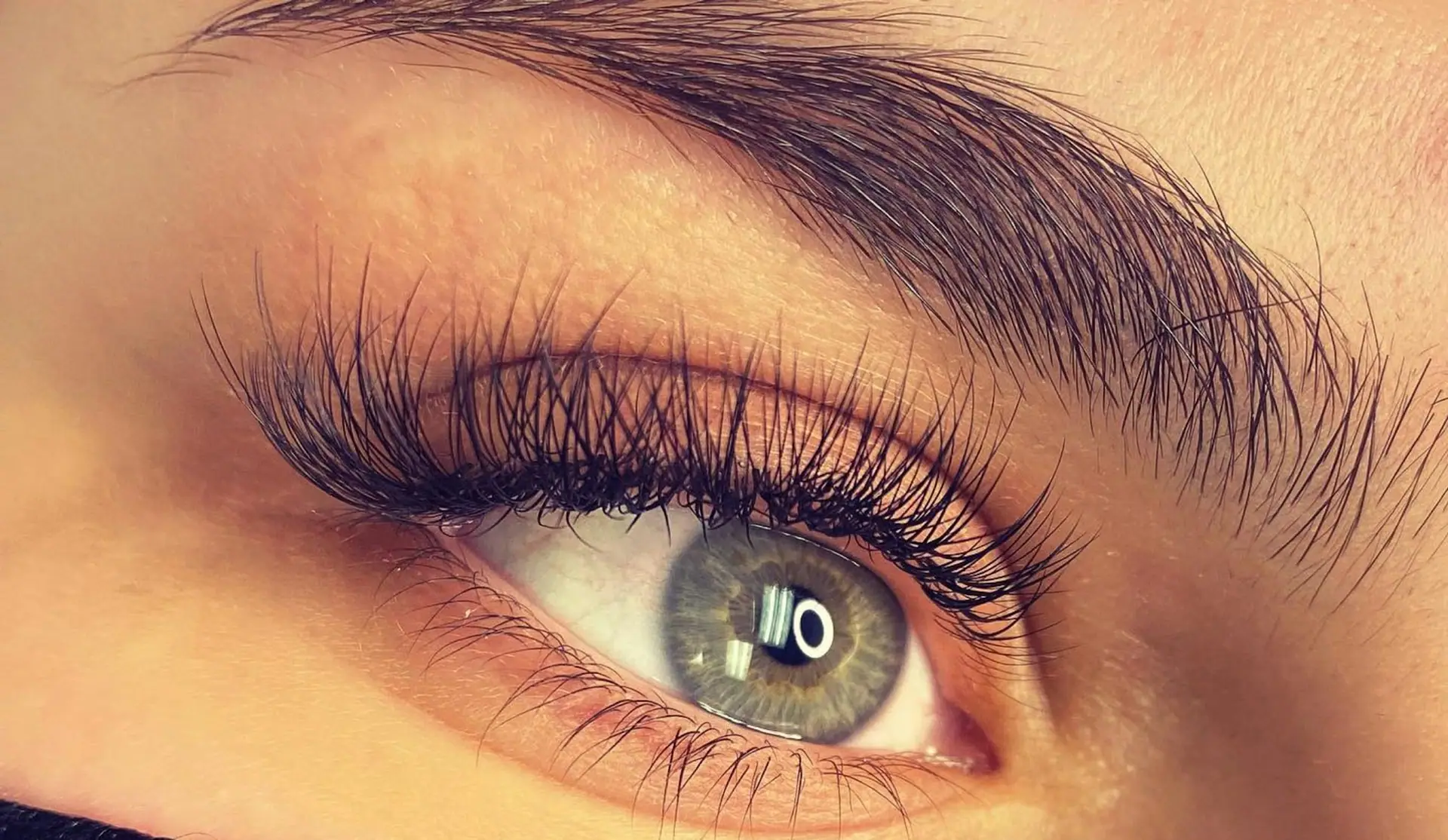Close-up of long, curled lashes beneath a groomed brow