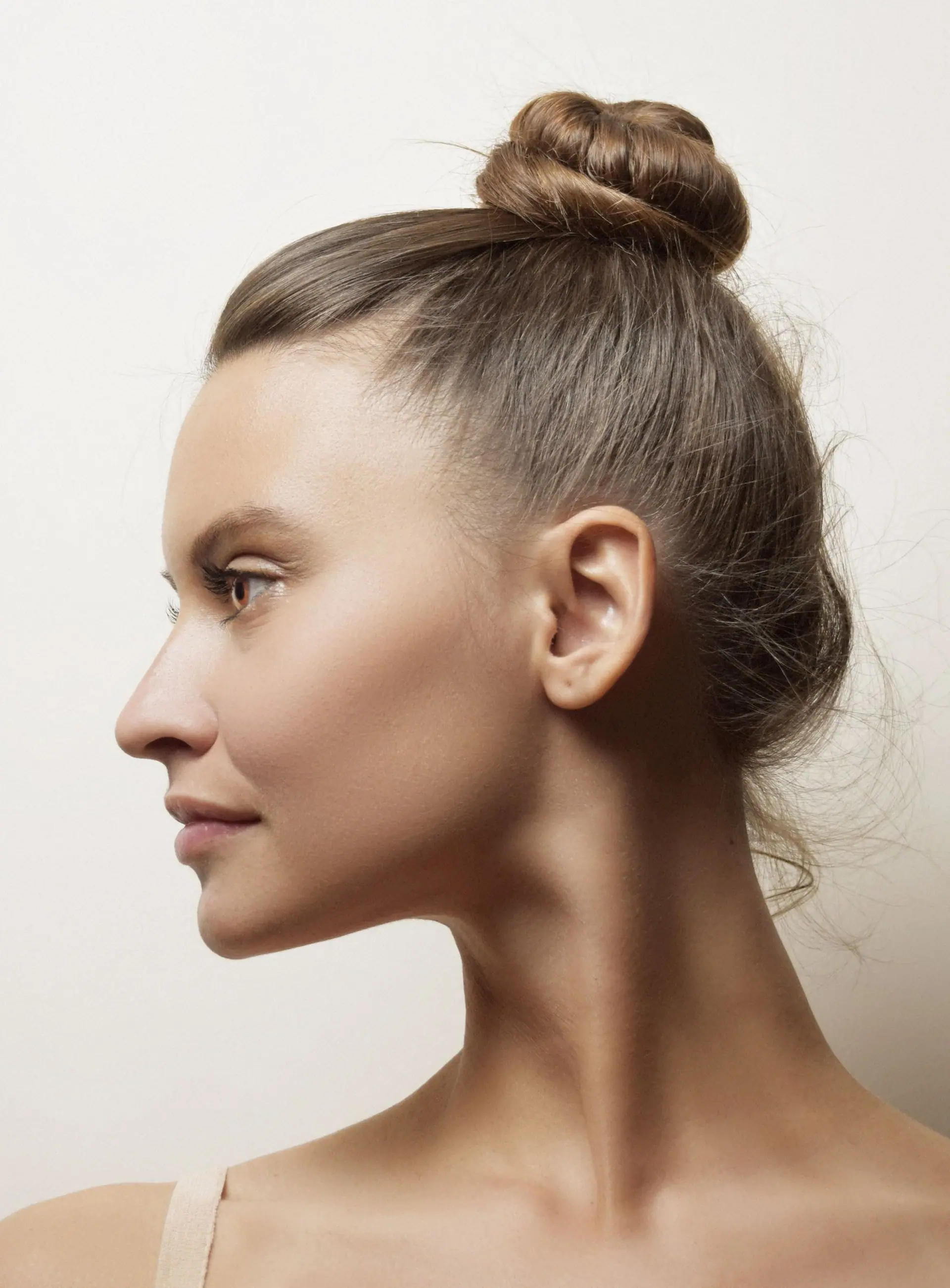 Side profile of a woman with softly groomed brows and her hair in a bun